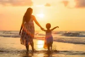 Maman et fille sur la plage au coucher du soleil