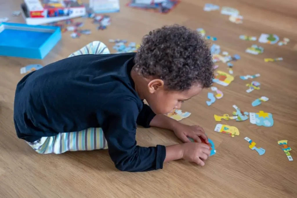 Enfant appliqué sur un puzzle pour 4 ans et travaillant sa motricité fine