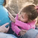 Petite fille touchant le ventre de sa mère enceinte