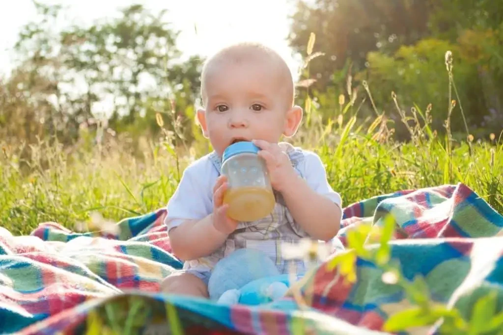 Bébé en train de boire du jus de fruit au biberon