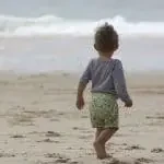 Bébé sur la plage faisant face à la mer