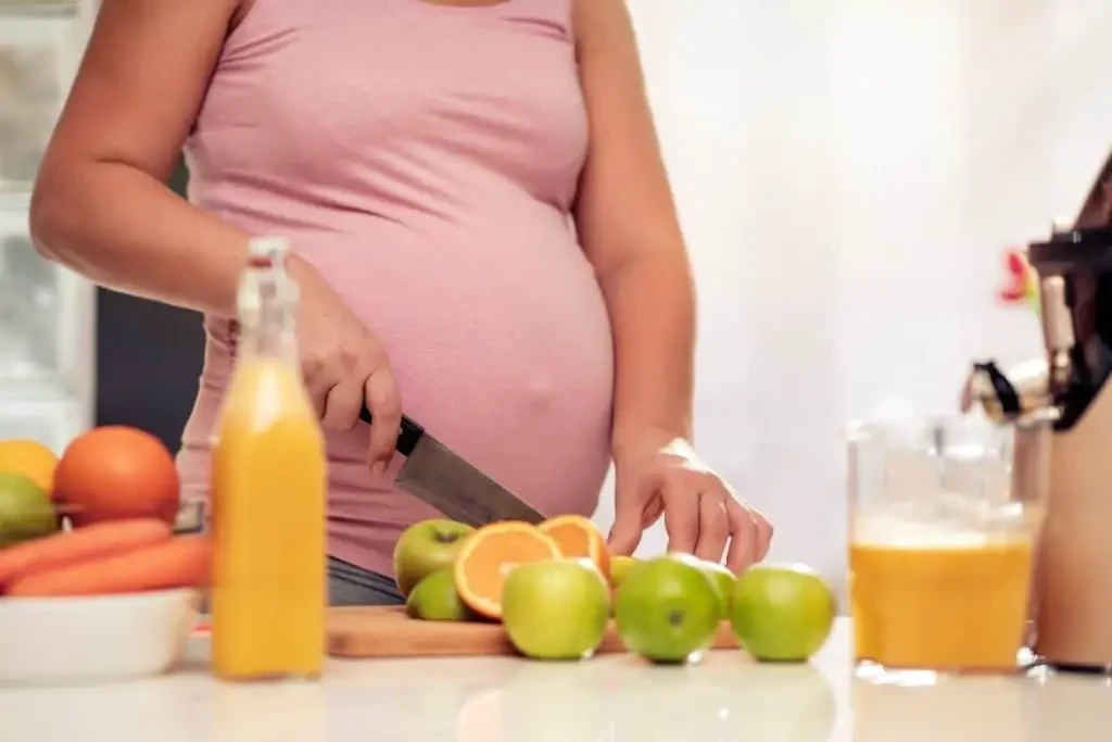 Femme enceinte préparant un jus de fruits frais