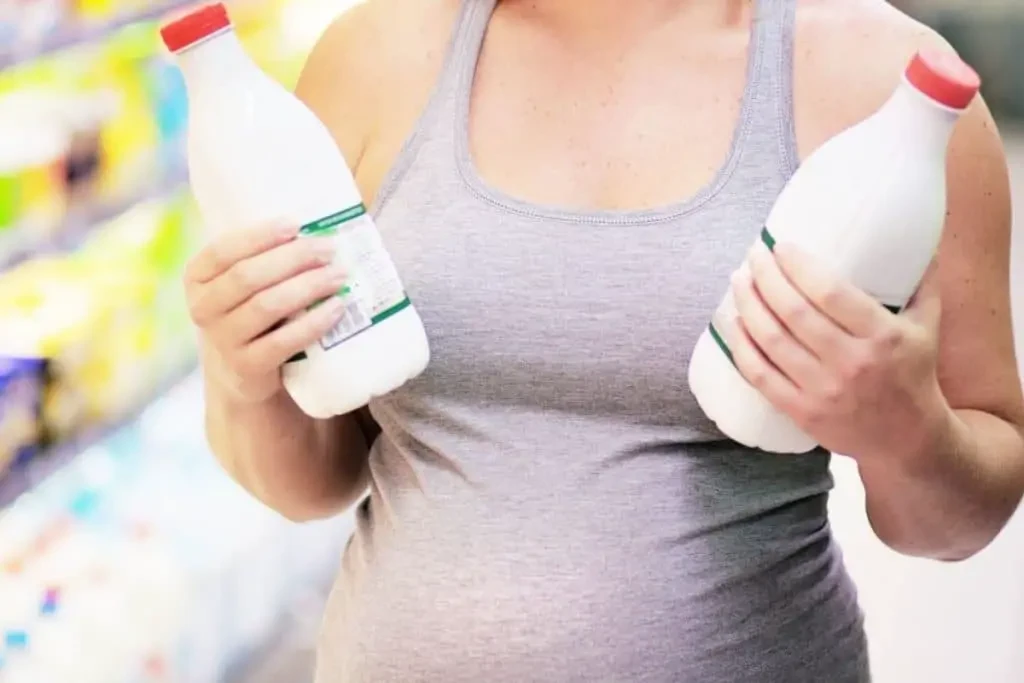 Femme enceinte tenant des bouteilles de lait