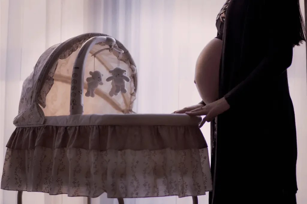 Femme enceinte debout à côté d'un berceau pour bébé